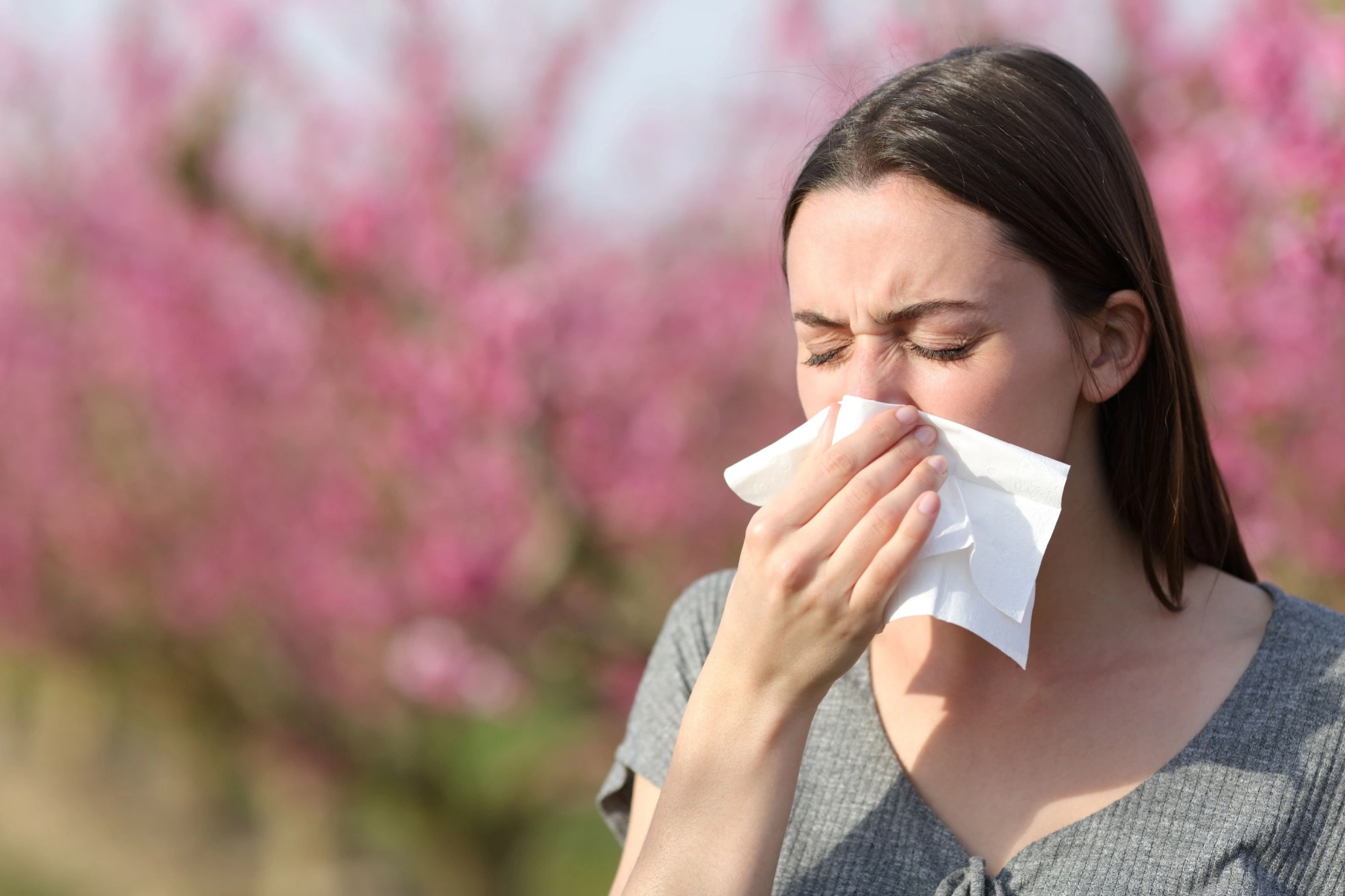 Woman sneezing into a tissue with bad allergies